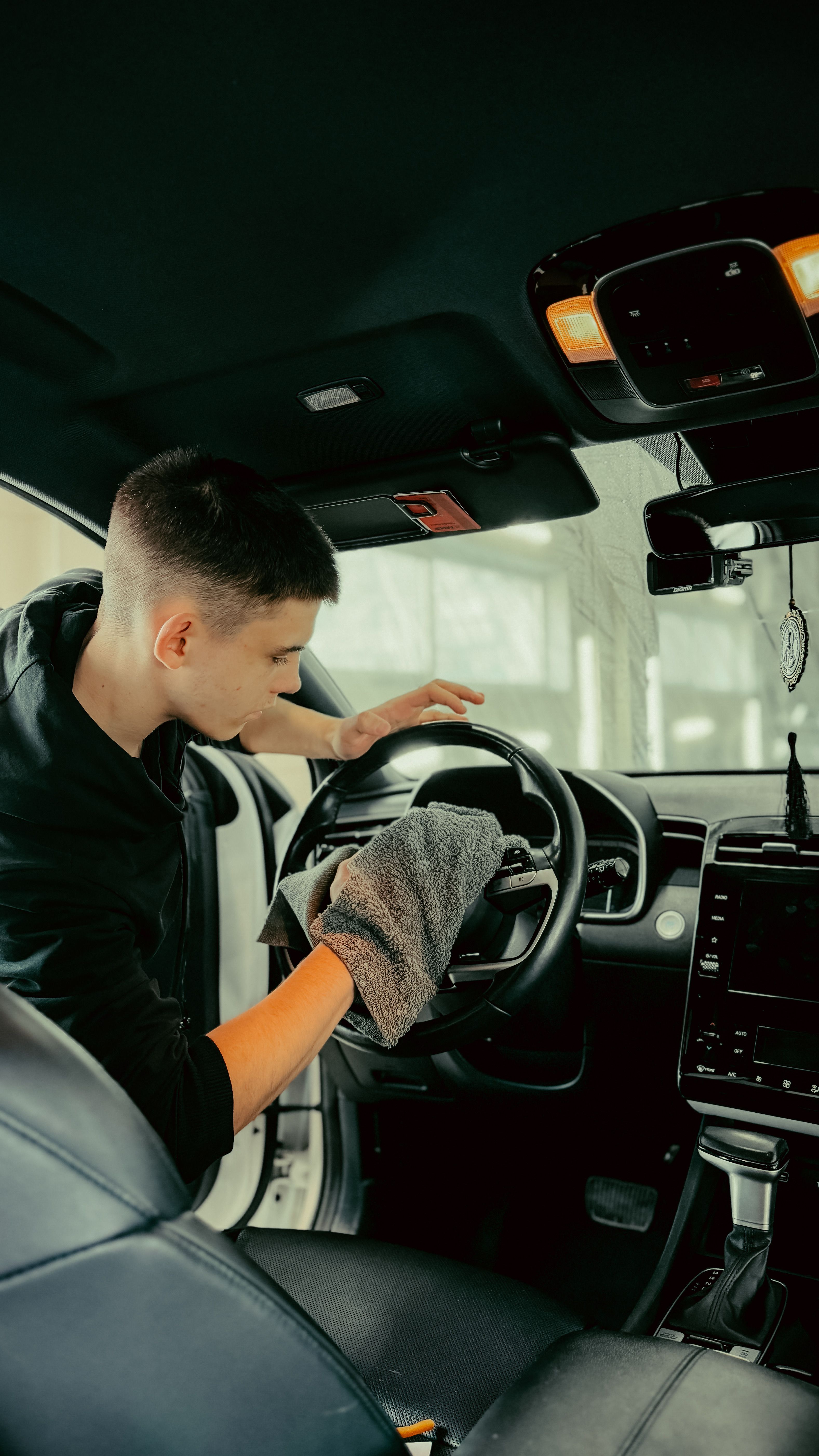 Team member hand-detailing a car interior with a microfiber towel